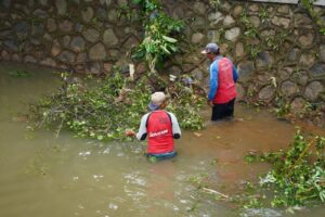 Petugas memberikan dahan dan daun yang dapat menghalangi alur air sungai.